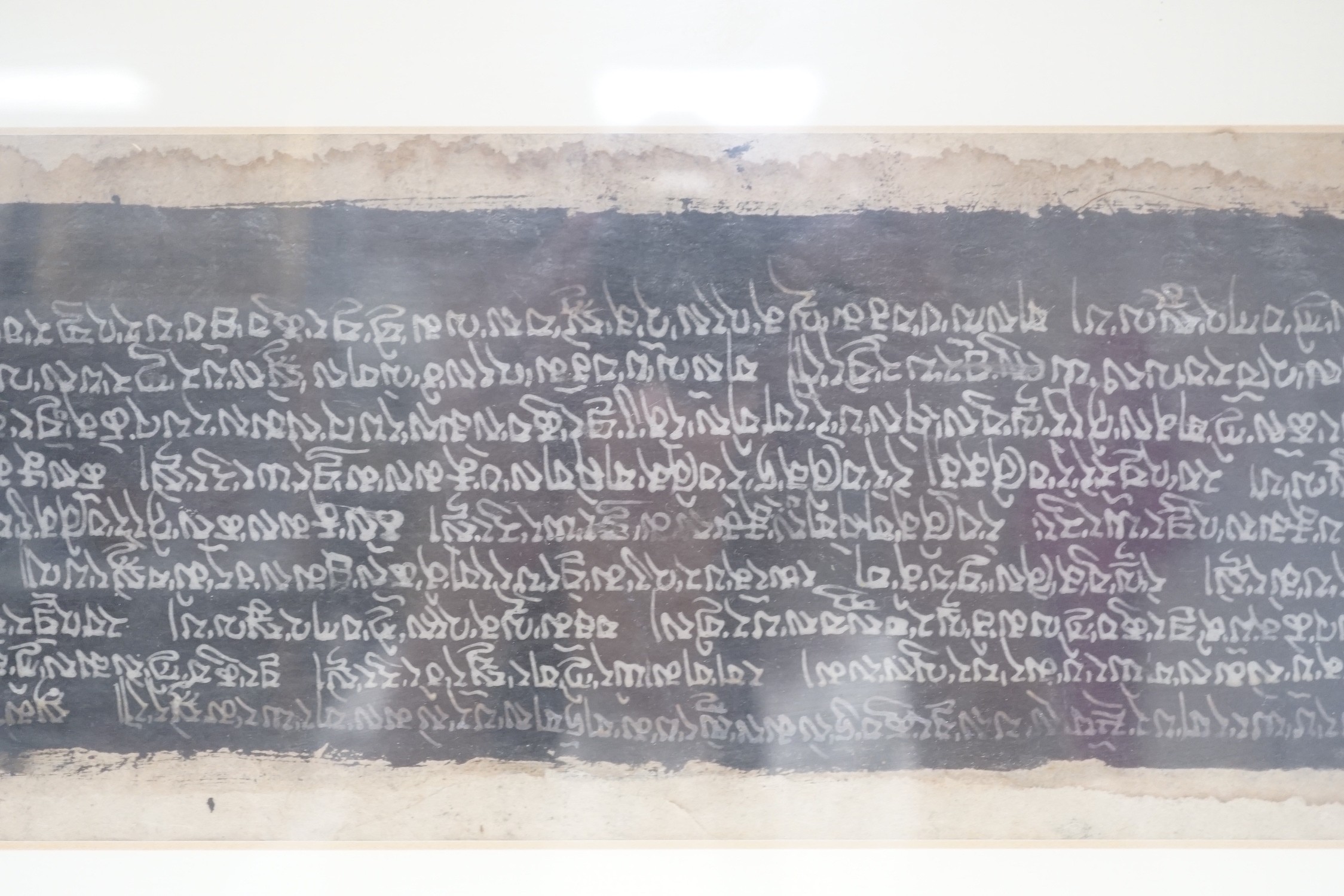 A framed Tibetan Sanskrit sutra panel, 45cms x 13cms.